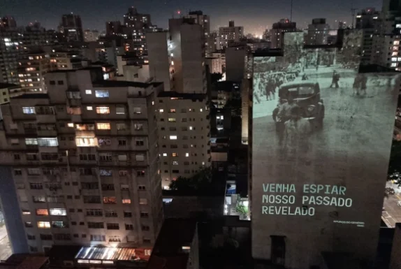 Projeção "Venha espiar nosso passado revelado" em empena de edifício em São Paulo